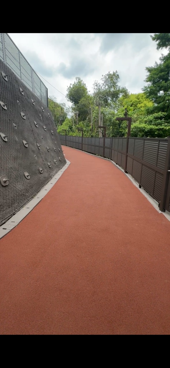 神田川口から続く赤い舗装の屋外通路。左側に壁、右側に柵がある